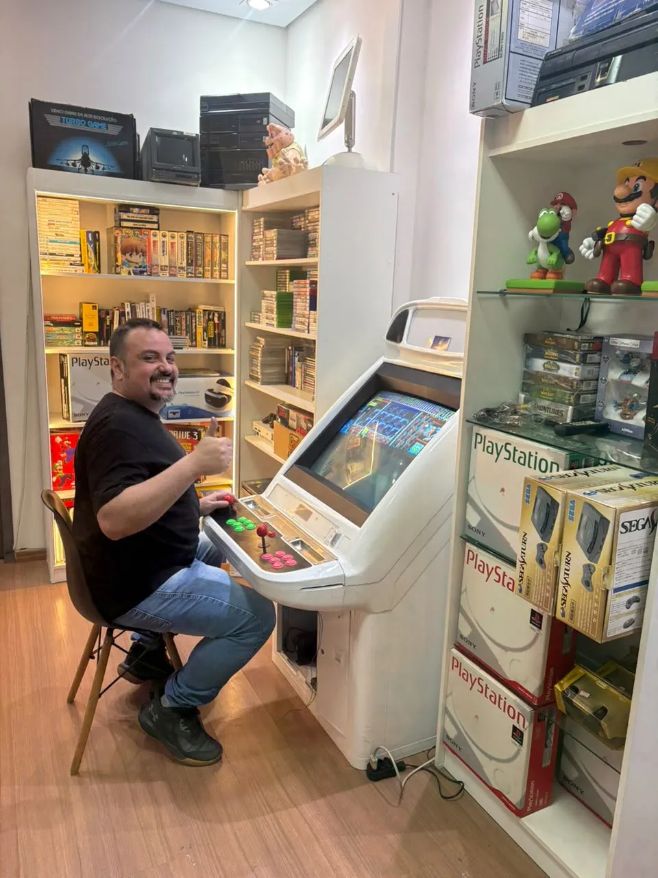 Renato, da Game Lab, sentado em um arcade na loja