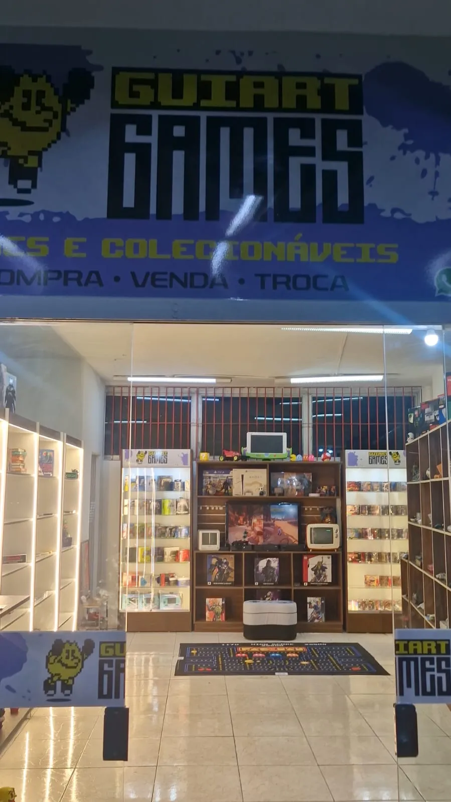Entrada da loja Guiart Games, no Jabaquara, com letreiro e estantes