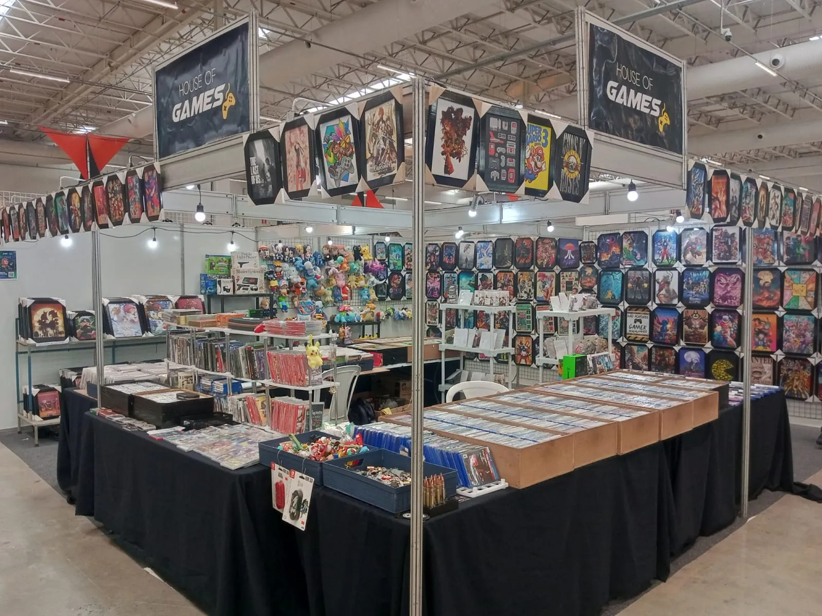 Estande da House of Games em evento, com mesas de jogos e quadros nas paredes